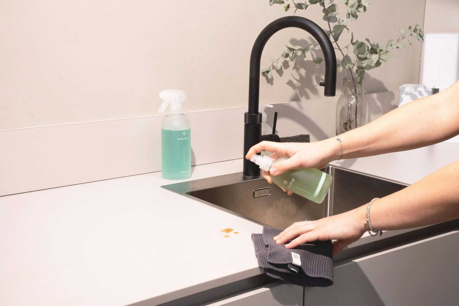 A professional cleaner wiping down a modern kitchen worktop